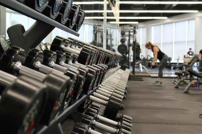 A woman is lifting dumbbells in the gym