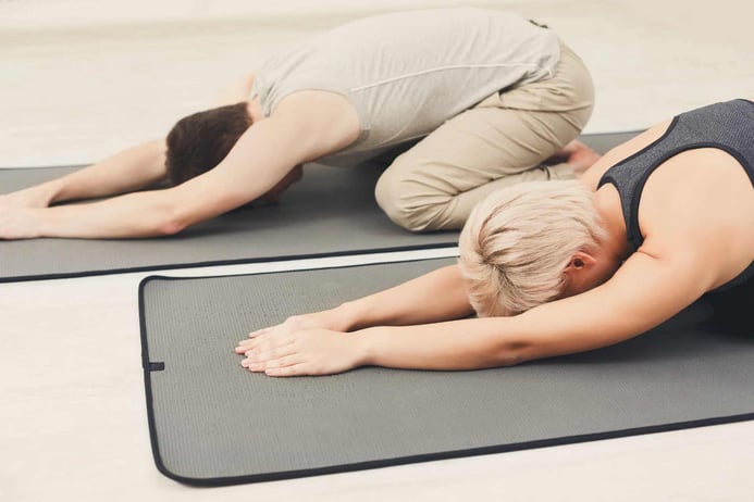 Couple training yoga in childs pose