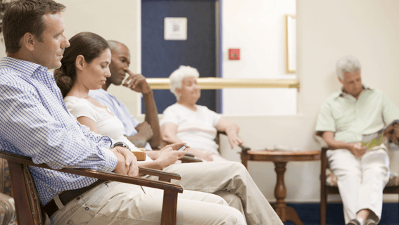 A number of people sitting in a waiting room