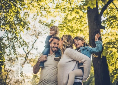 Healthy family piggy backing in the trees