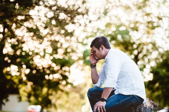 A man looking upset sitting in a park