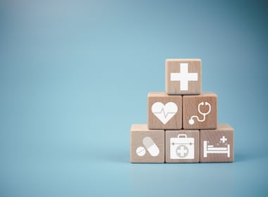 symbols of health, heart, medicine, stethoscope printed on wooden cubes stacked on top of each other