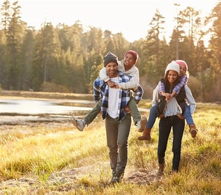 Family healthy walk in the countryside piggy-backing kids 