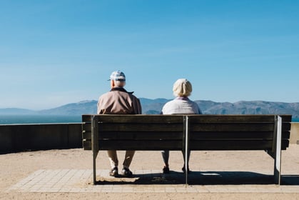 older couple sat on a bench overlooking moutains