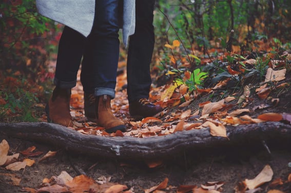 Two people walking through a leafy woods